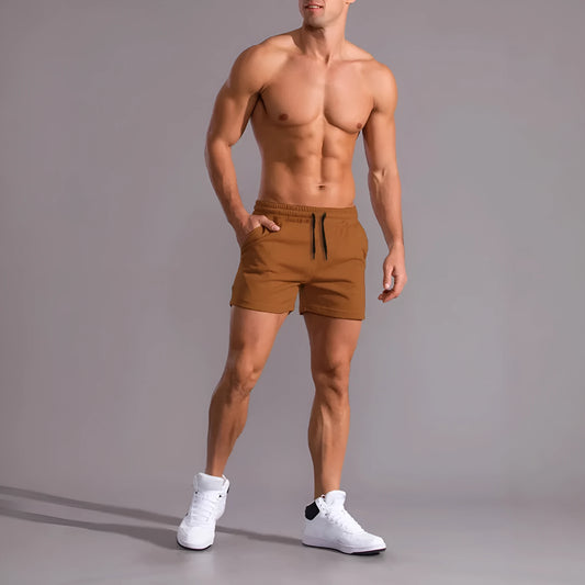 Three pairs of men's solid colour drawstring shorts in black, khaki, and light brown laid flat.