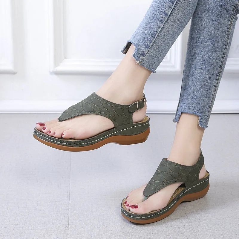 Women's wedge heel flip flop sandals in black with adjustable back strap on a light background