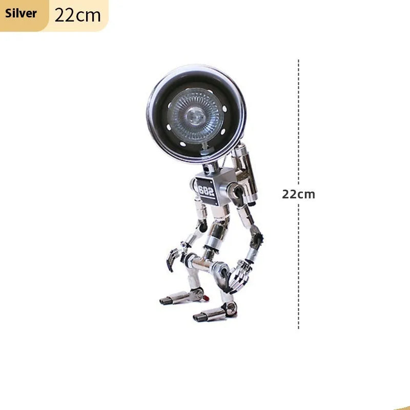 Silver metallic robot-shaped decorative desk lamp with internal LED glow on a wooden surface.