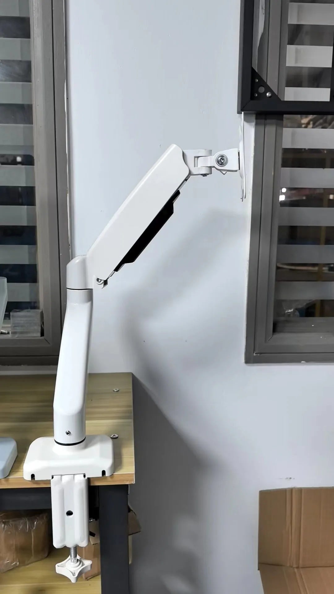 Black rotating telescopic LCD screen bracket elevated on a table.