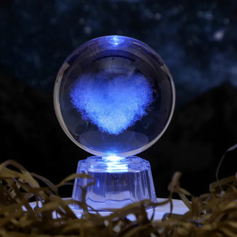 Transparent crystal ball ornament with inner carving of clouds, shown on a wooden table.