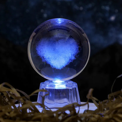 Transparent crystal ball ornament with inner carving of clouds, shown on a wooden table.