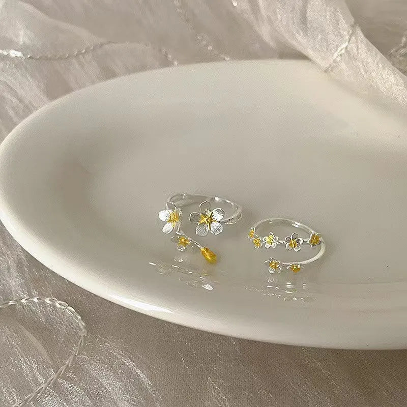Adjustable open-mouth ring with a detailed three-dimensional jasmine flower design in a metallic finish.