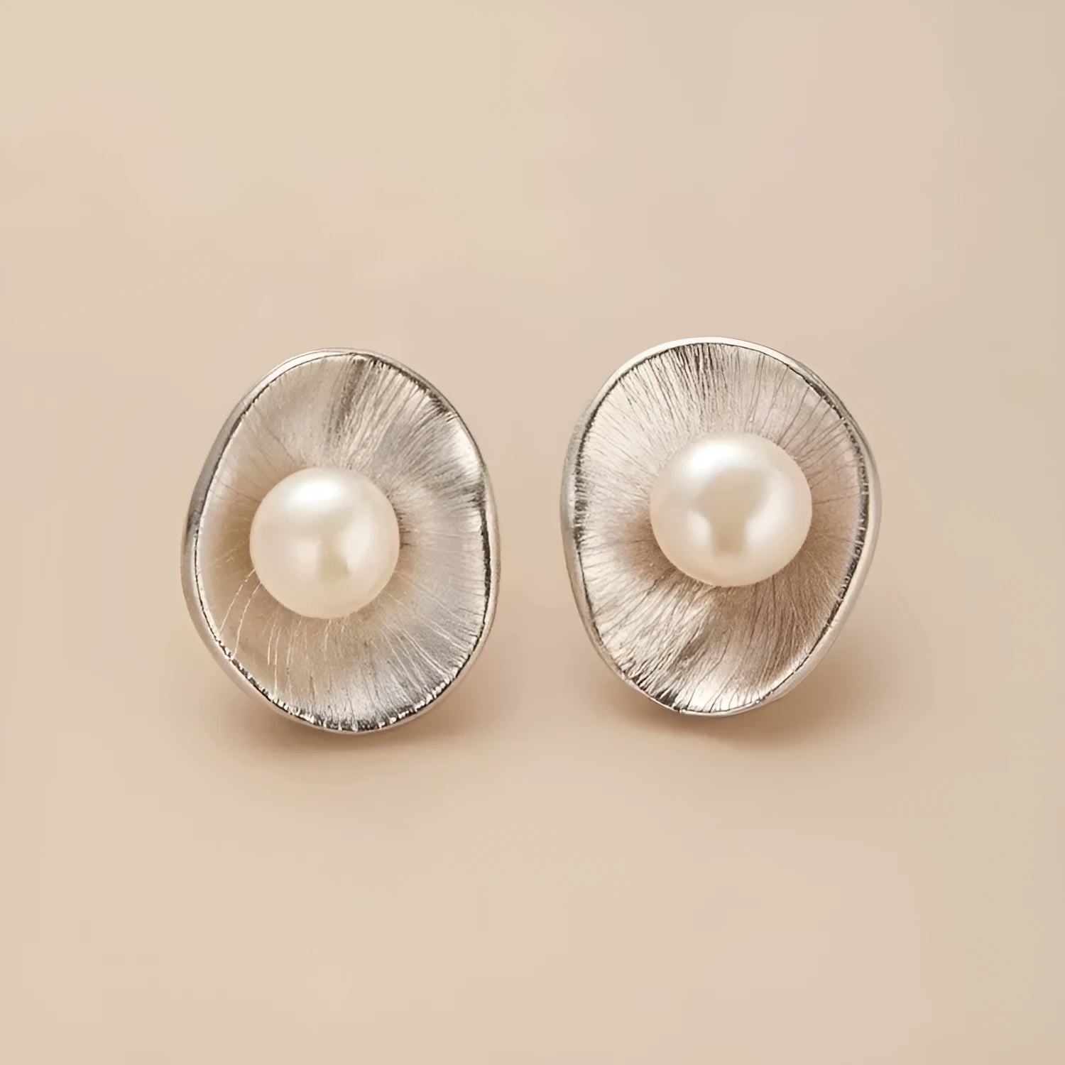 A pair of gold-coloured geometric sterling silver stud earrings with white pearl accents on a white background.