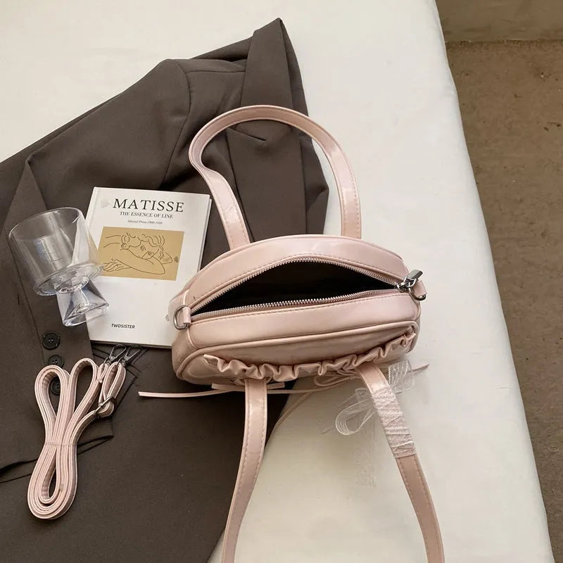 Milky white women's shoulder handbag with a large bandage bow and visible stitching, showing the internal phone pocket.