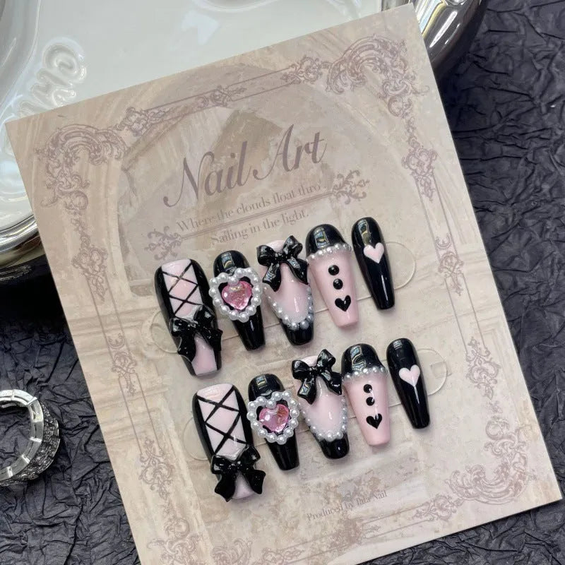 Hand-painted black and pink heart false nail set with detachable bow ornament, shown in sizes XS to L.