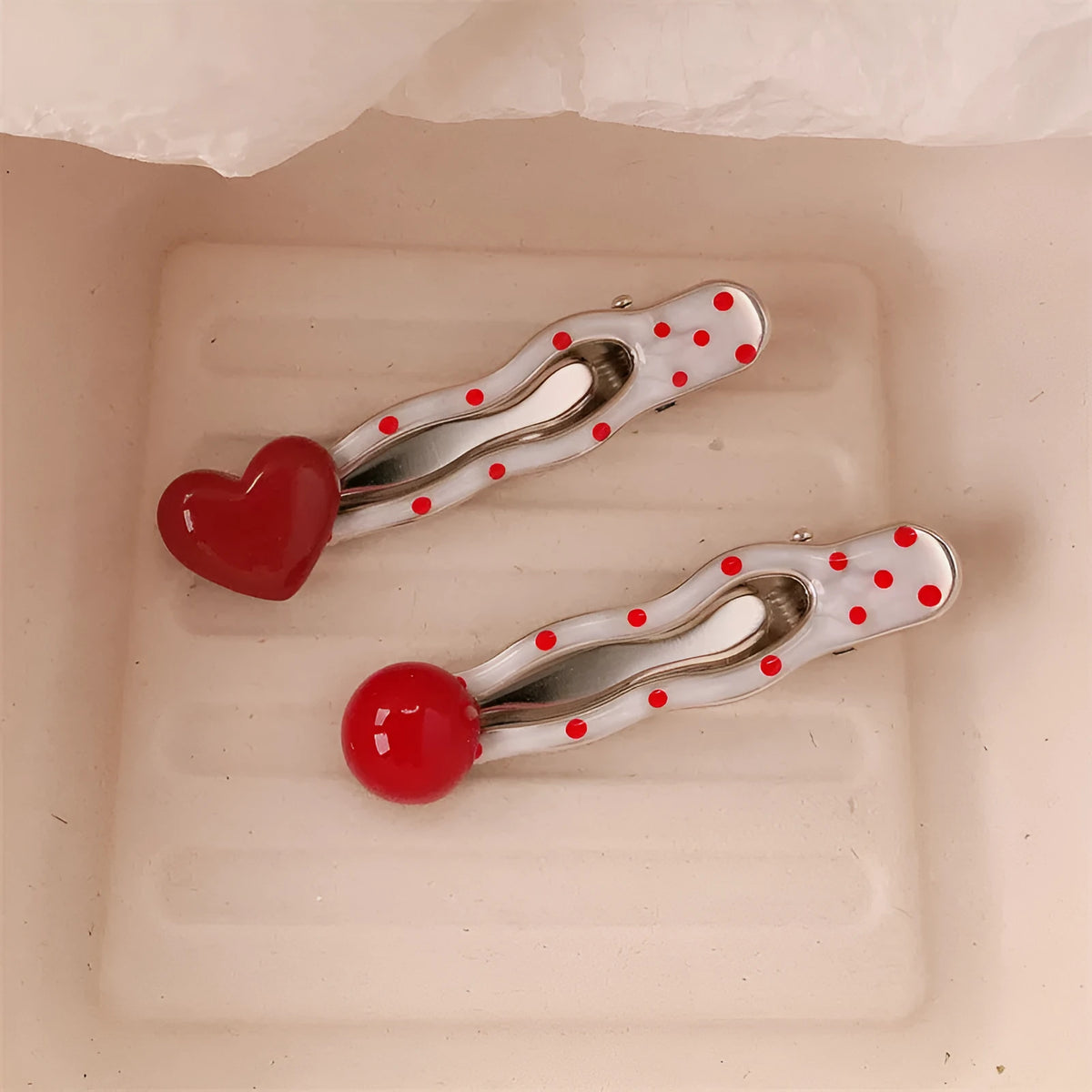 Red plastic hair clip with a 3D love heart and dots on a willow leaf-shaped base.