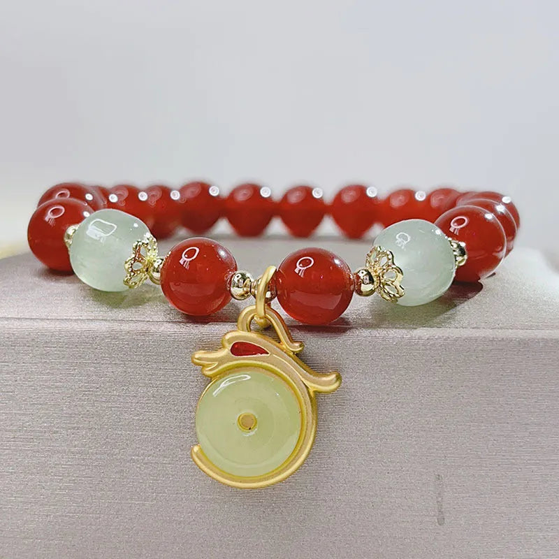 Close-up of a red agate bracelet featuring a detailed dragon design in a Chinese style.