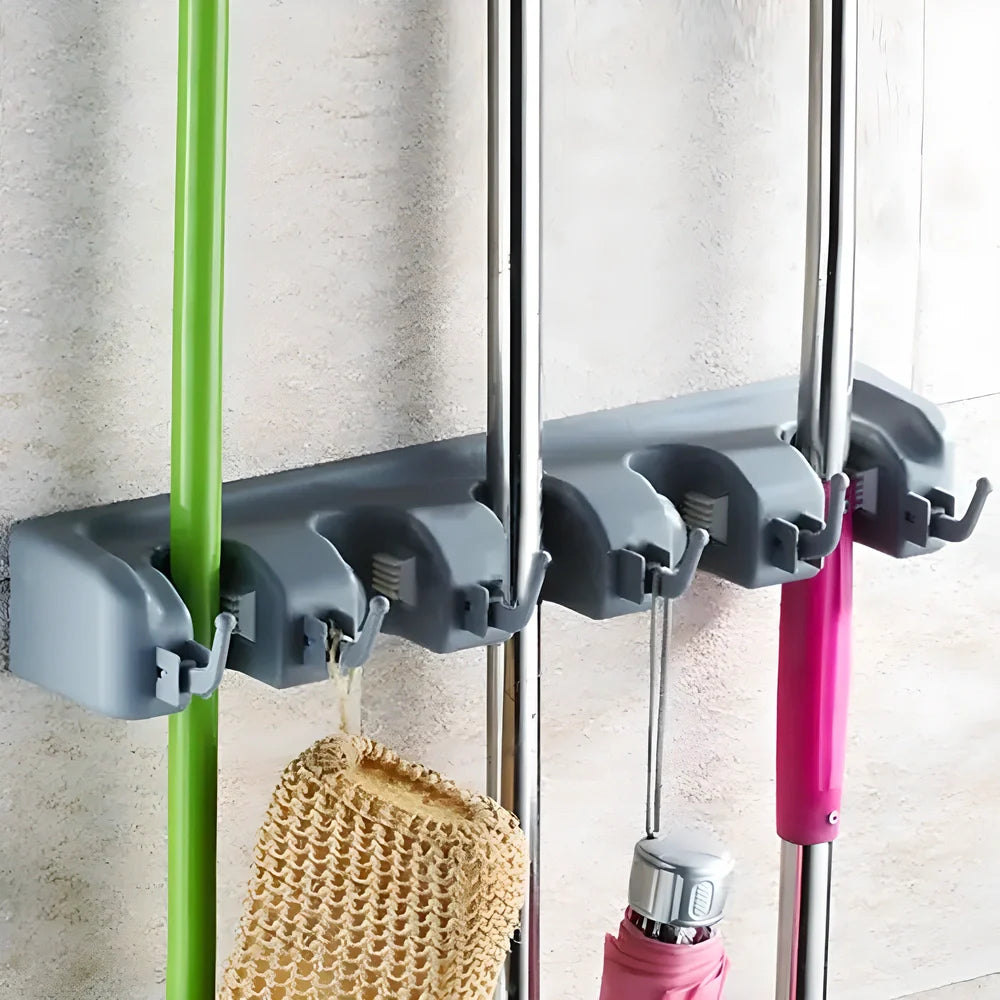 Wall-mounted organizer rack holding multiple mops, brooms, and cleaning tools in a tidy, organized manner